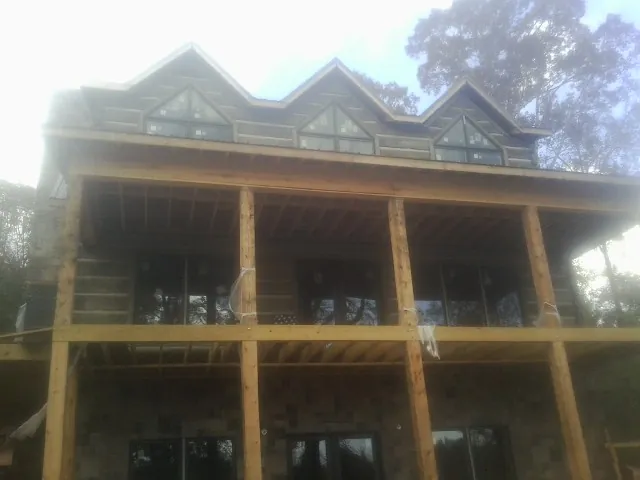Dormers and porch framing on a large log home under construction — Roof Coating work by our crew in Big Sky