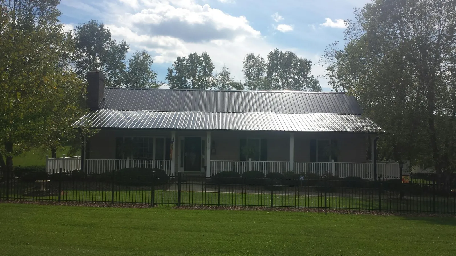 Gray metal roof on a brick ranch with a full width front porch — Gutter Guard Installation work by our crew in Big Sky