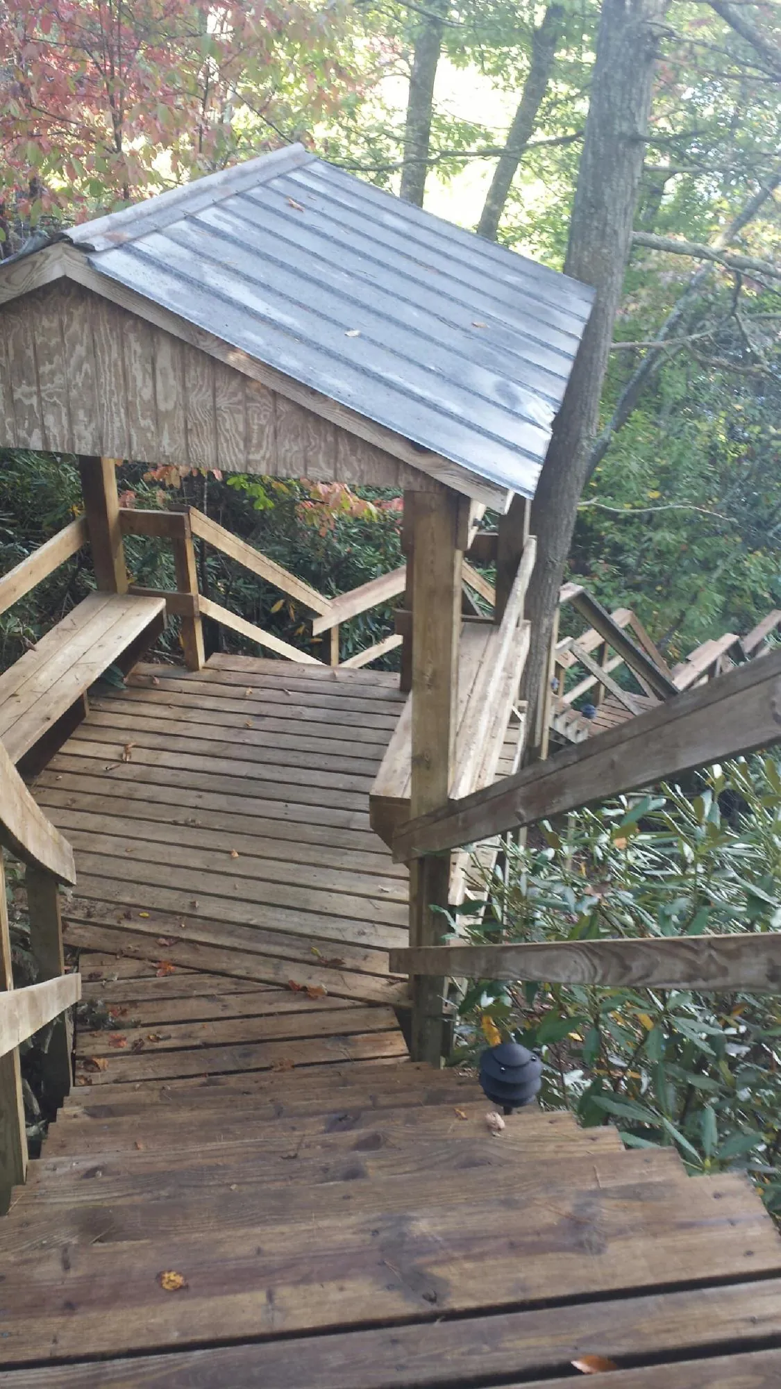 Metal roofed shelter over wooden steps on a wooded walkway — Skylight Repair & Installation work by our crew in Big Sky