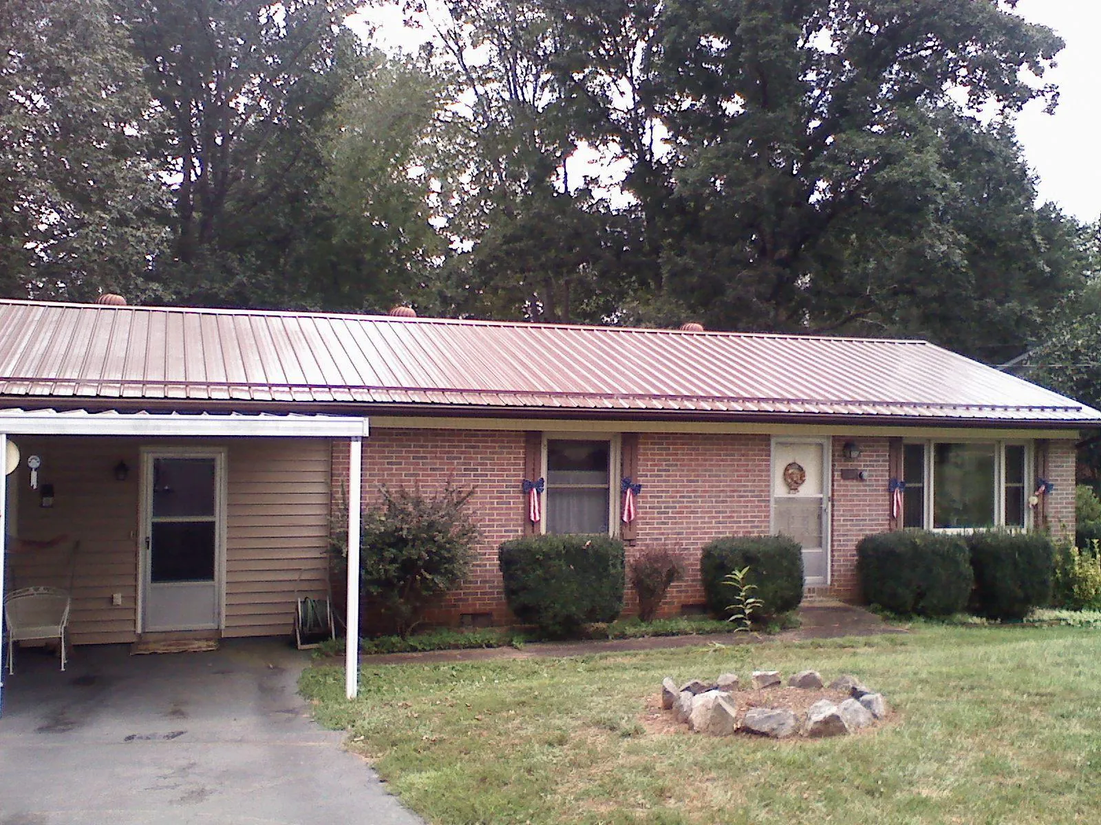 Bronze metal roof and carport on a brick ranch home — Roof Repair work by our crew in Big Sky
