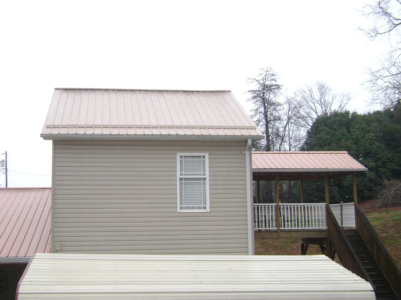 Tan metal roofs on a two story addition and attached porch, from a Roof Replacement job in Big Sky