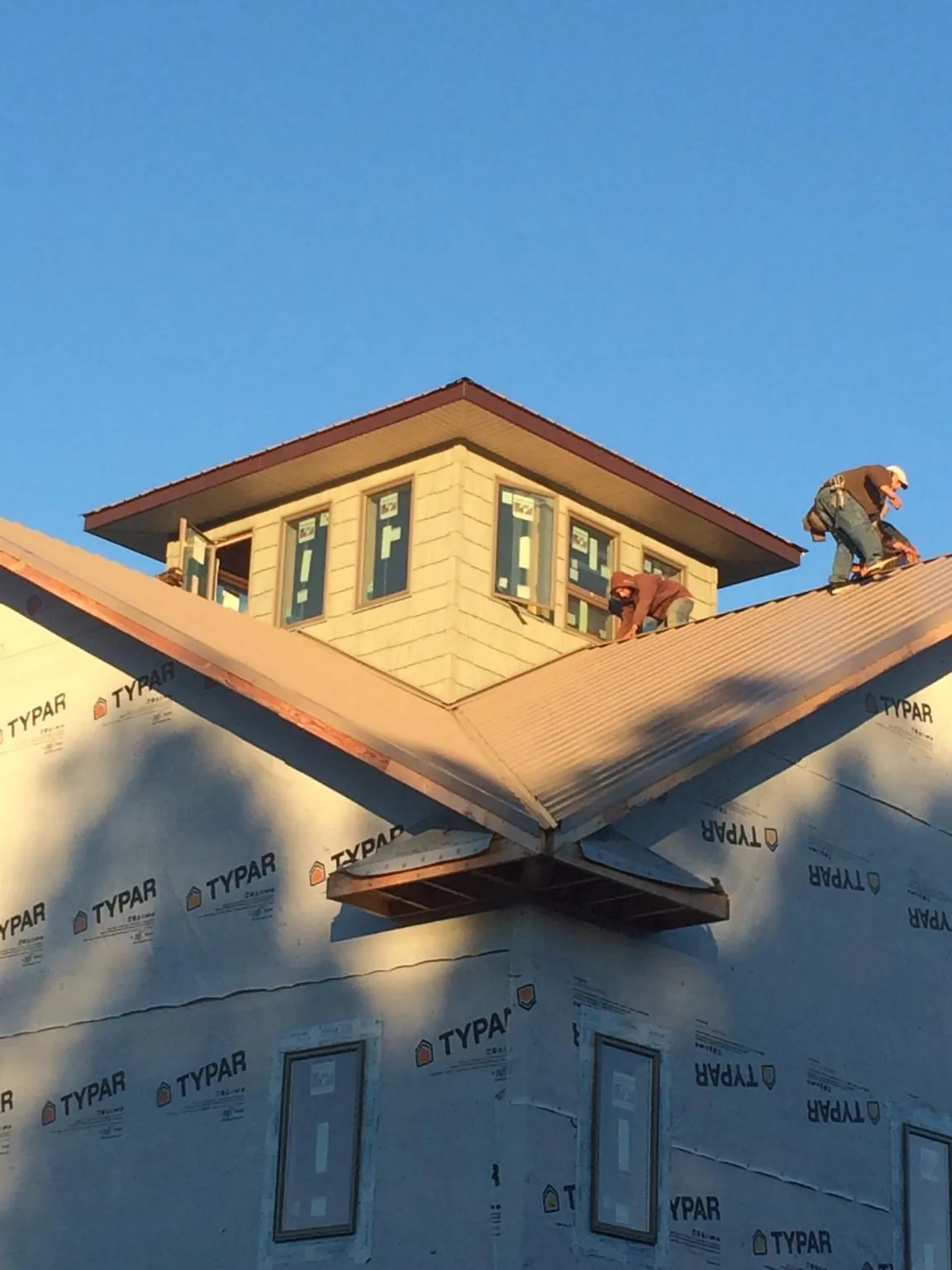 Roofers working around a rooftop cupola on a new metal roof at sunset — Roof Waterproofing in Big Sky by Roofing Brothers